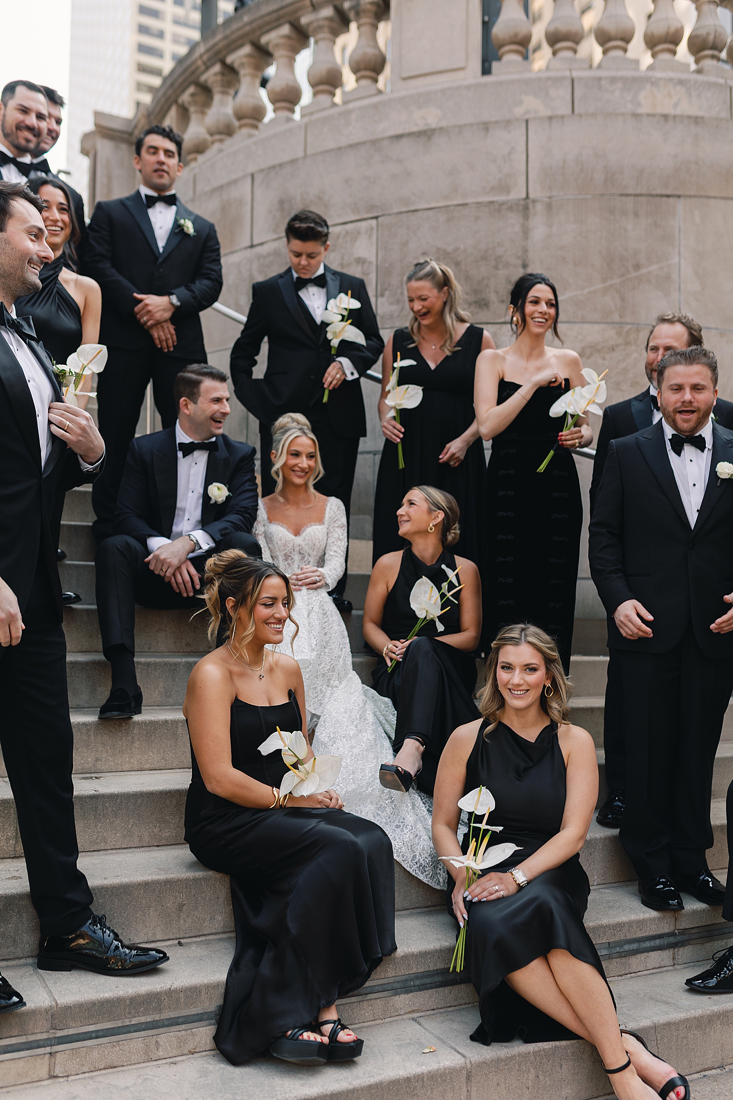 bridal party in black sit with couple on steps before ceremony at RPM Events