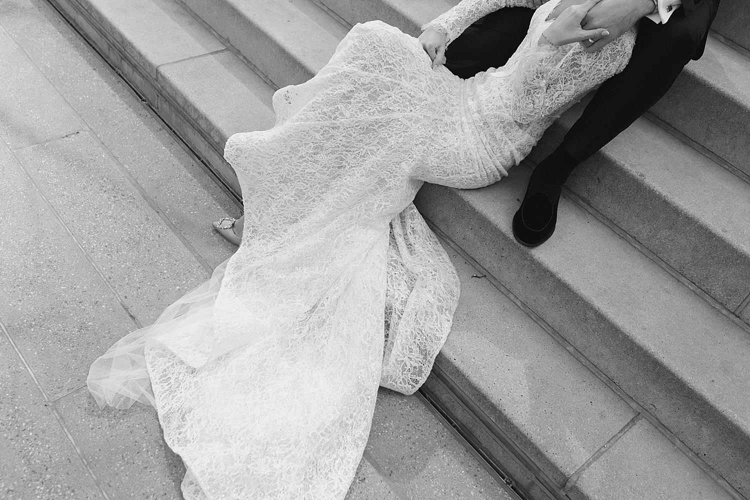 woman in white lace dress lies on lap of man in suit by Rachel Andrade Photography