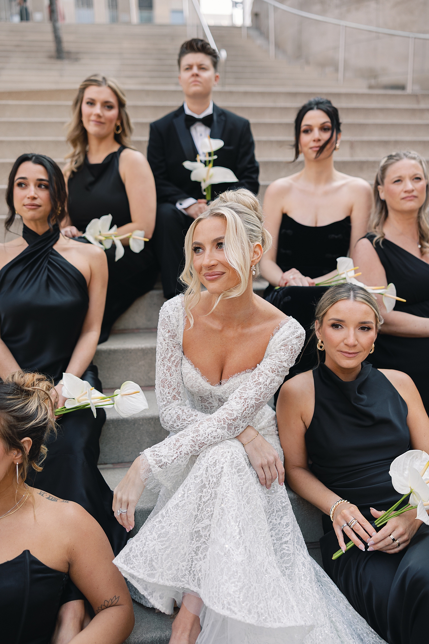 blond bride sits on steps surrounded by friends by Chicago luxury wedding photographer