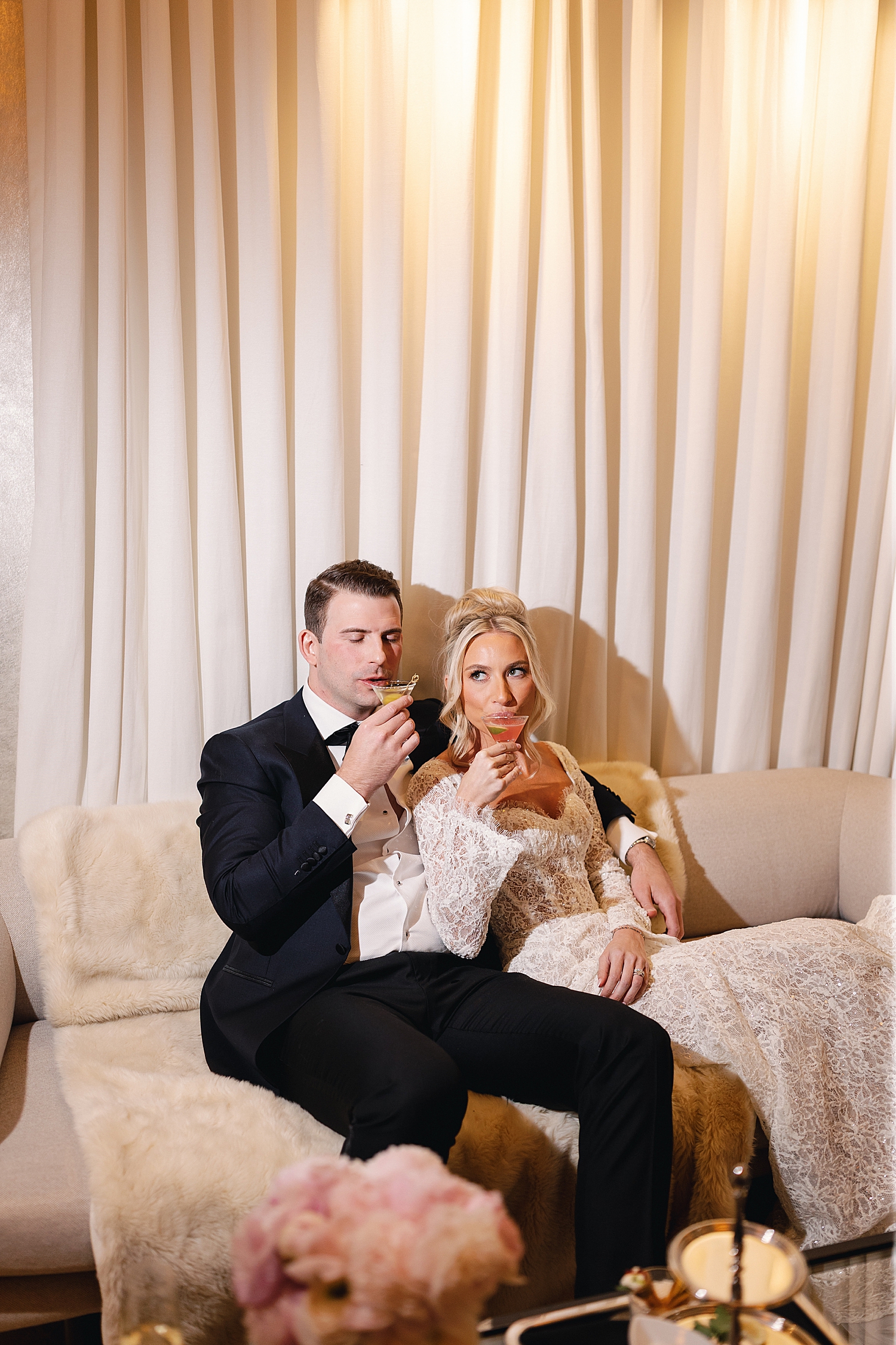 newlyweds share a cocktail on couch by Rachel Andrade Photography