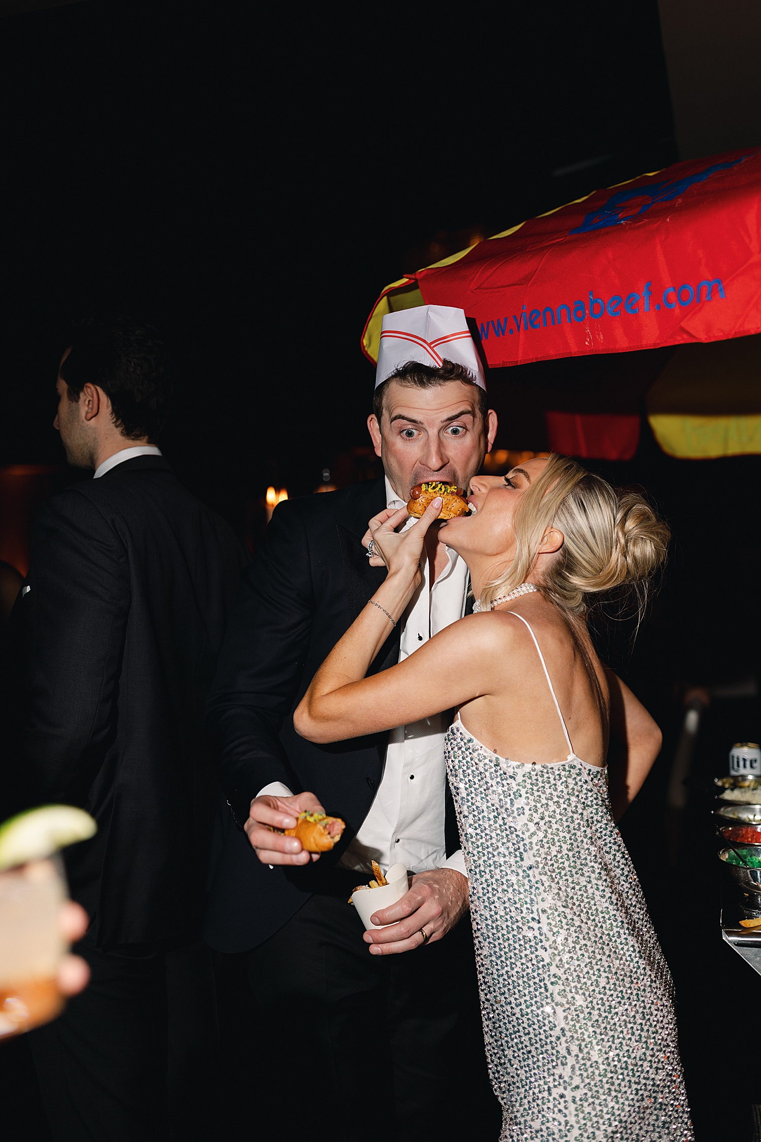 bride eats hot dog in sparkly dress by Chicago luxury wedding photographer