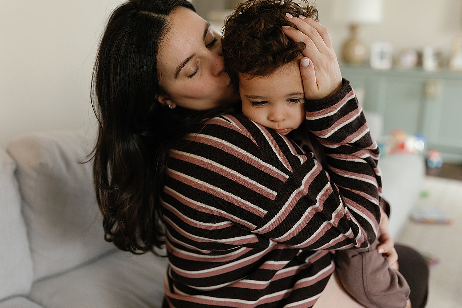 brunette mama holds little one on couch after learning how to style your family session