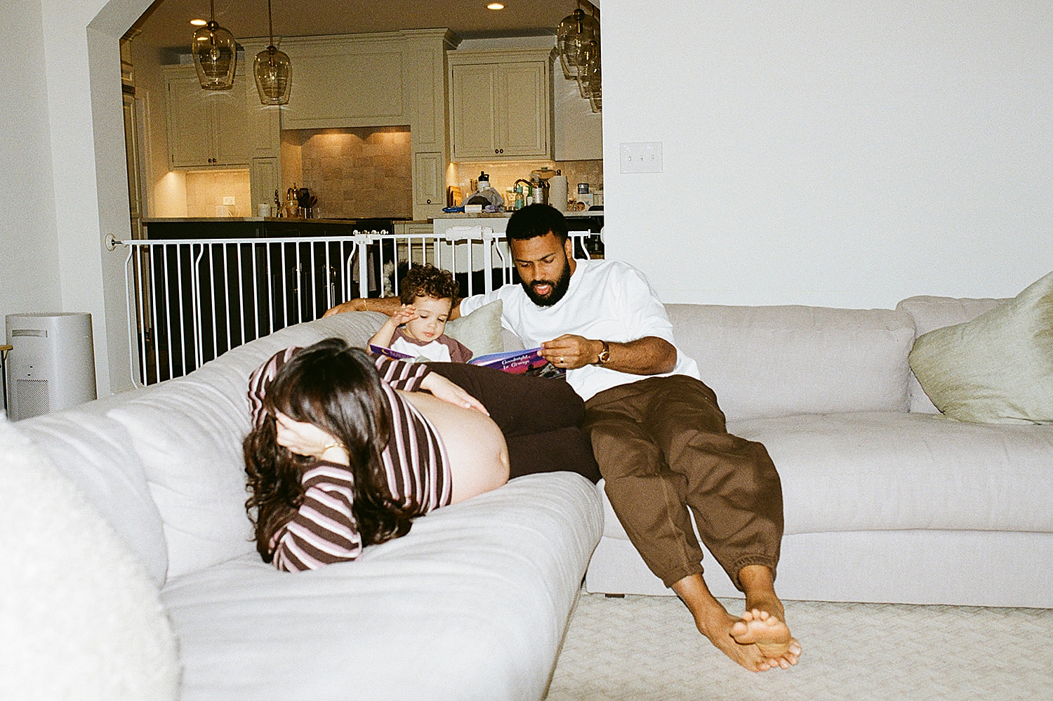 mom and dad lie on white couch with toddler by Chicago film photographer