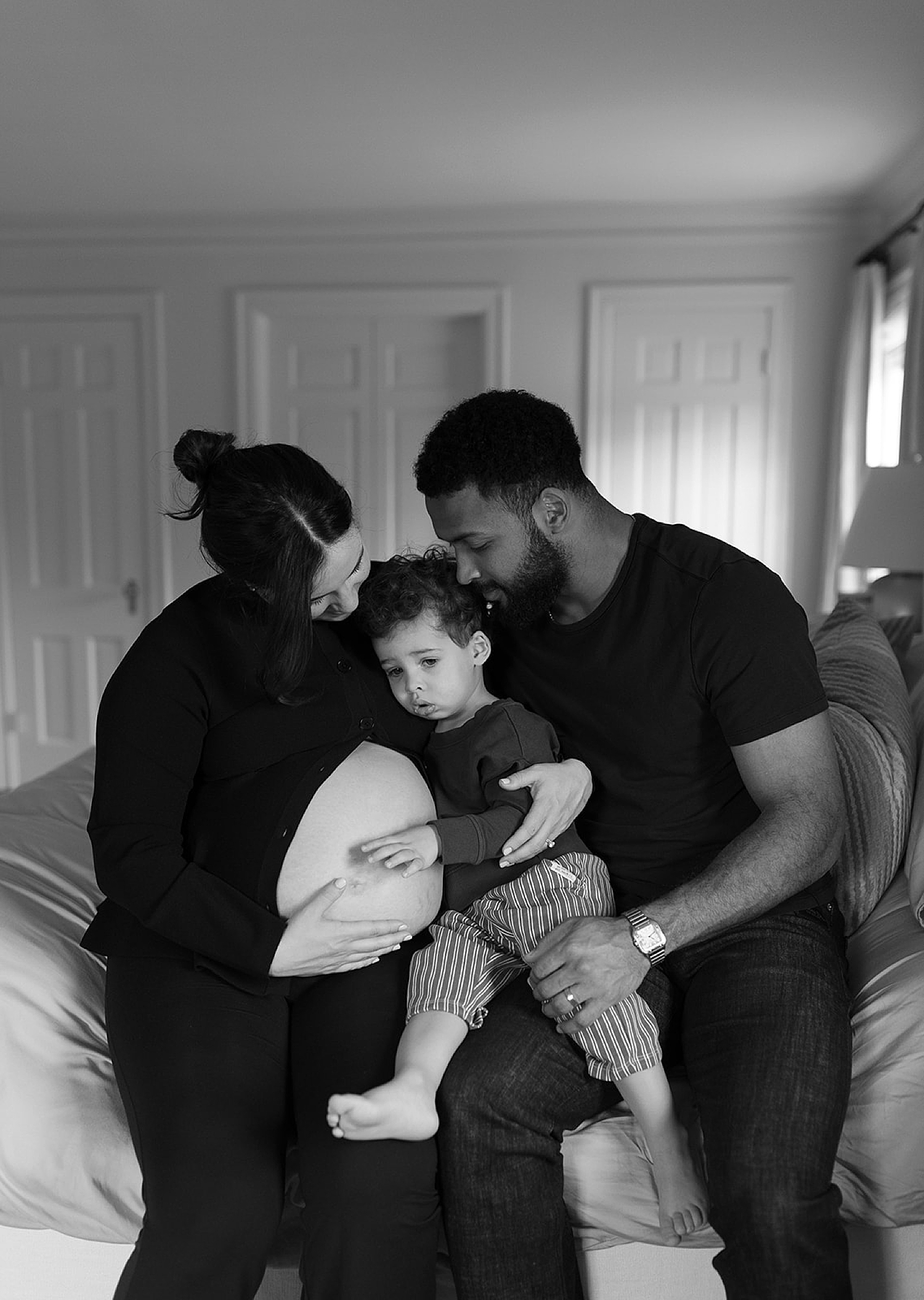 parents kiss their toddler while everyone wears black clothing after figuring out how to style your family session