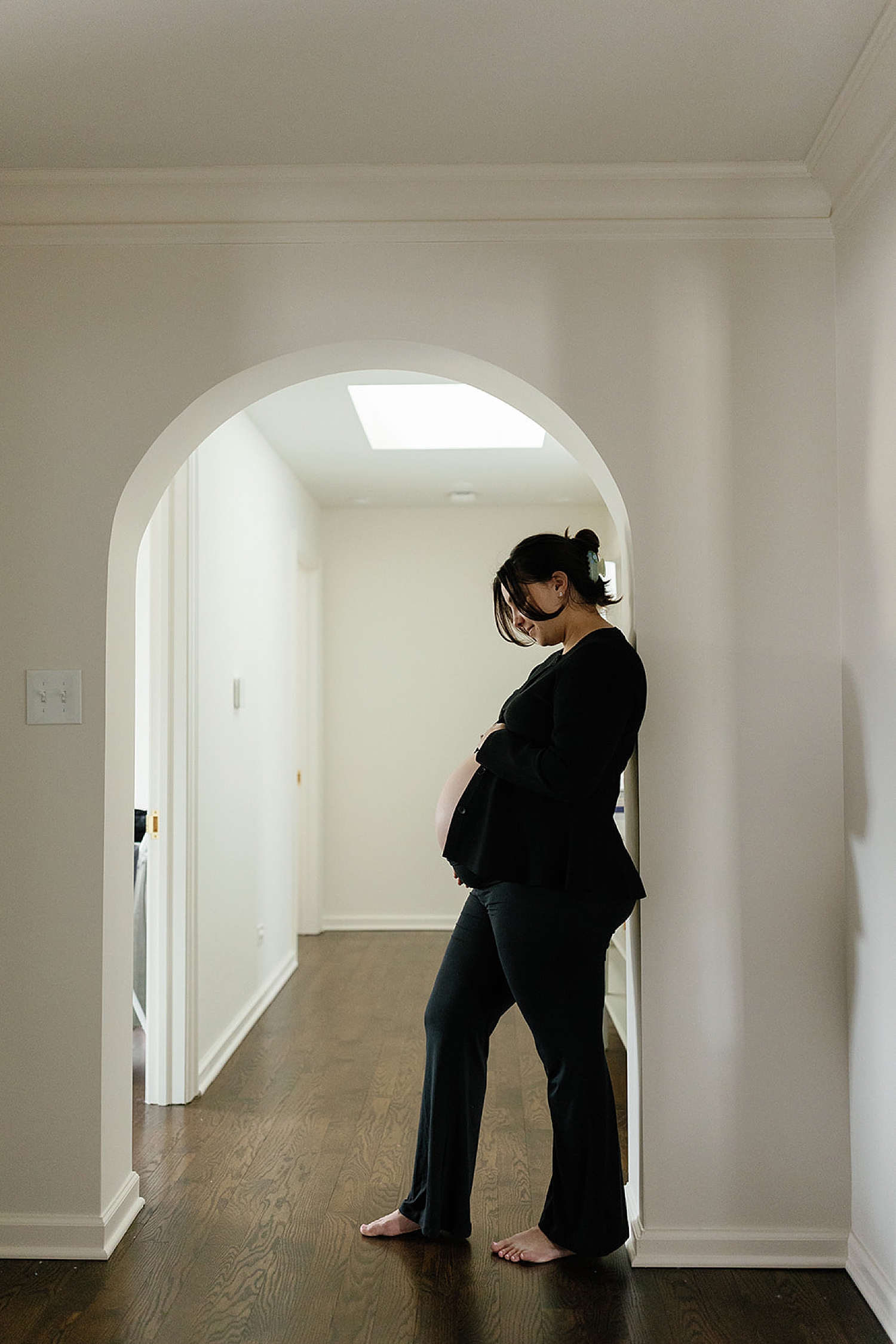 mother leans against archway in the hallway of home by Chicago film photographer