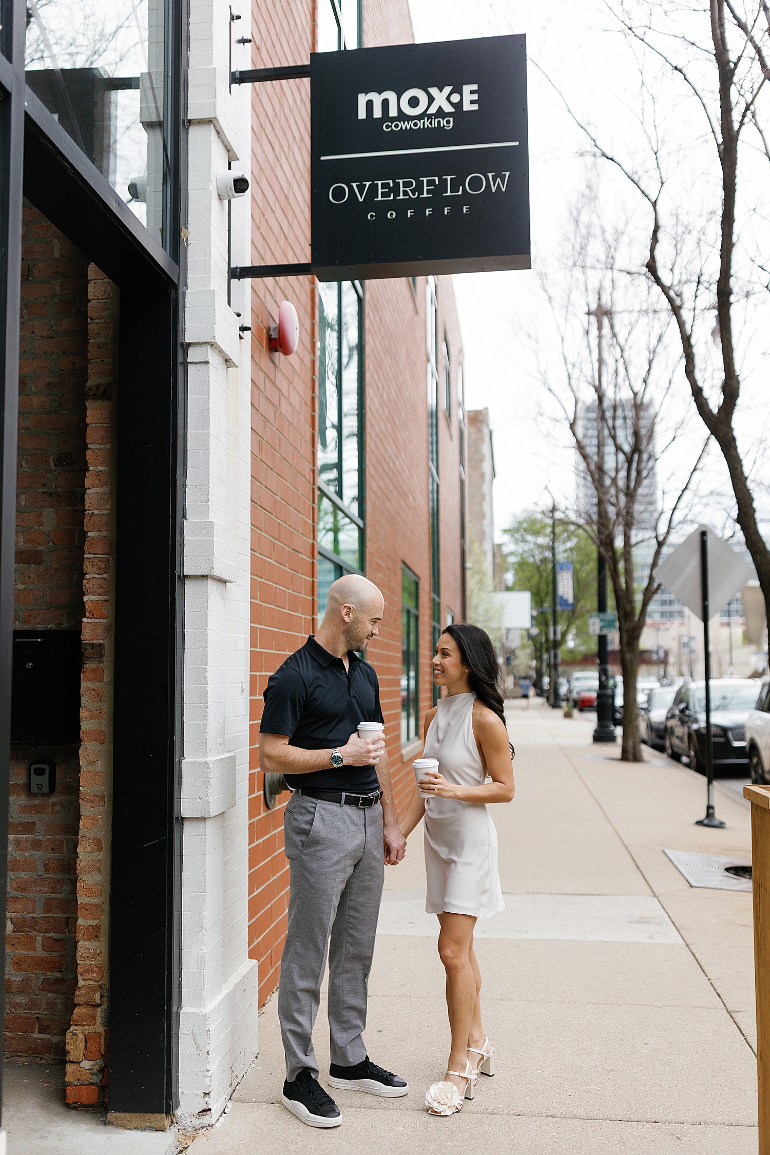 couple hold hands under coffee sign showing what to wear to your engagement session