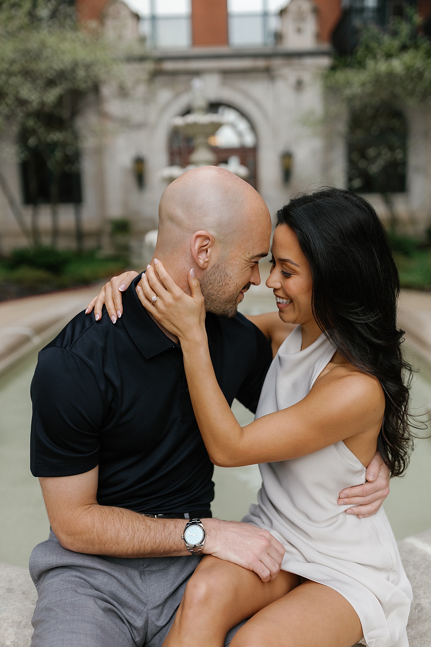 couple embrace while sitting on edge of fountain by Chicago wedding photographer