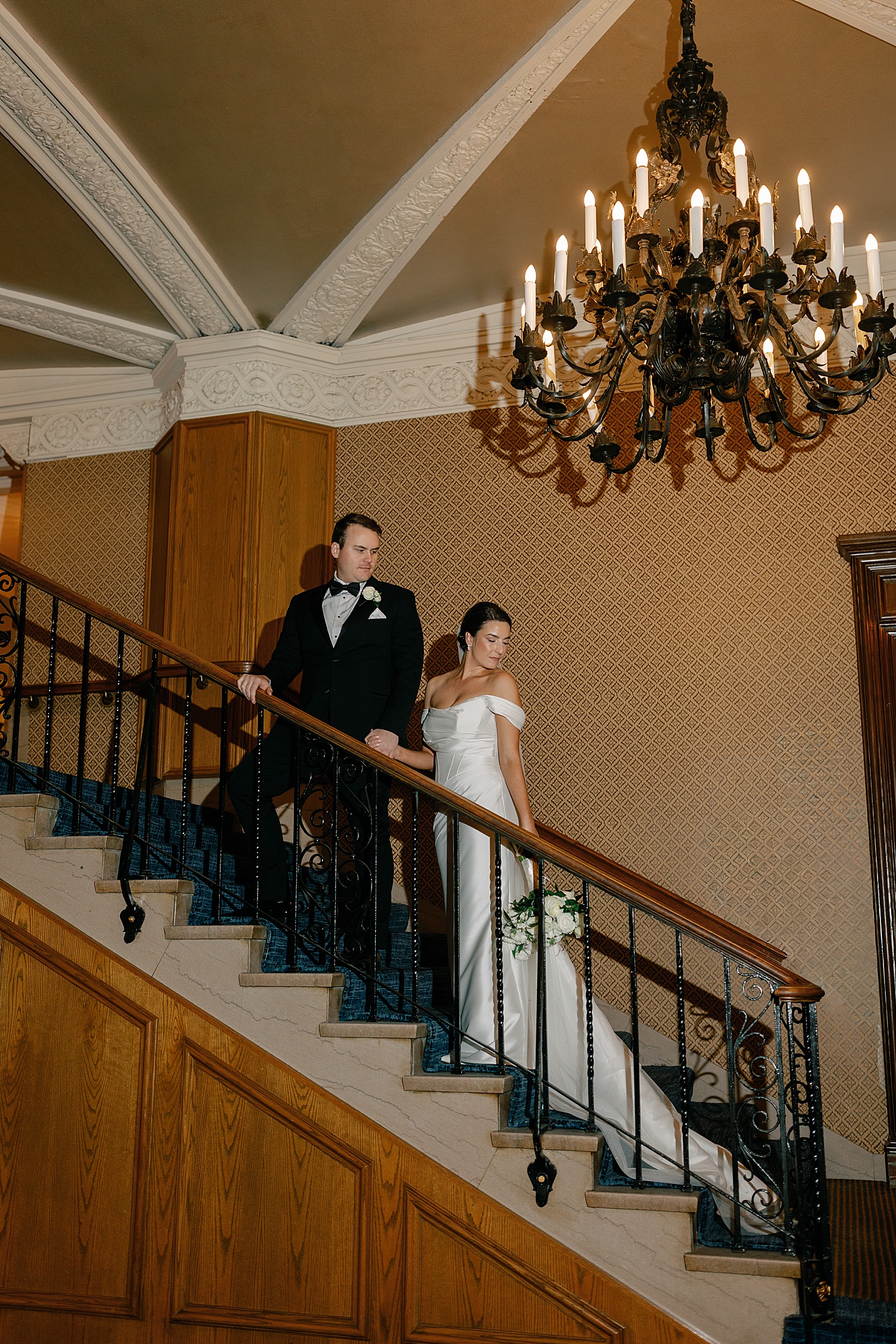 newlyweds stand on staircase after ceremony by Rachel Andrade Photography