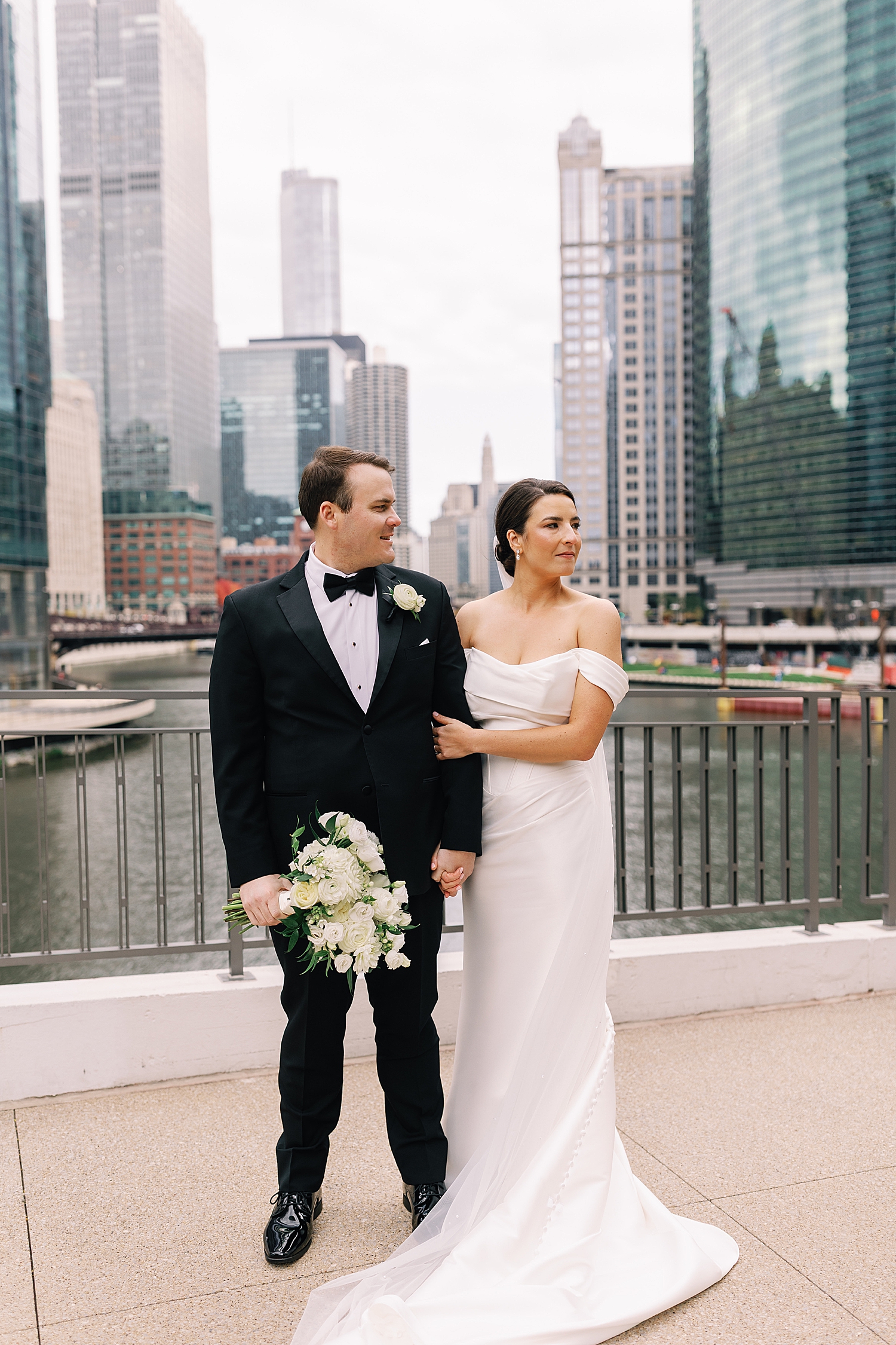 newlyweds stand next to water before ceremony by Chicago wedding photographer