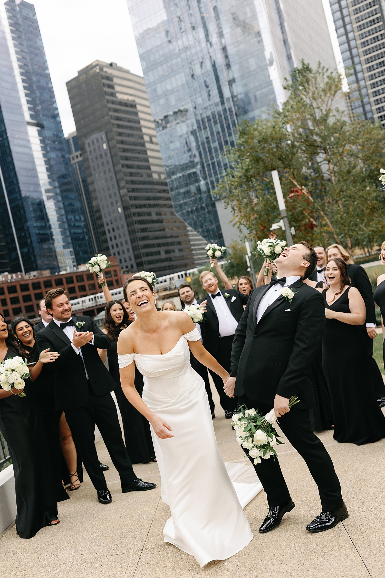 wedding party surrounds bride and groom outside on sidewalk by Rachel Andrade Photography