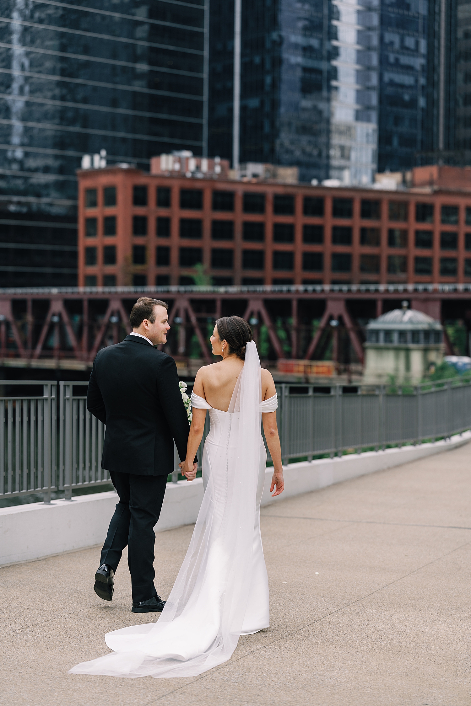 newlyweds walk next to water in downtown Chicago by wedding photographer
