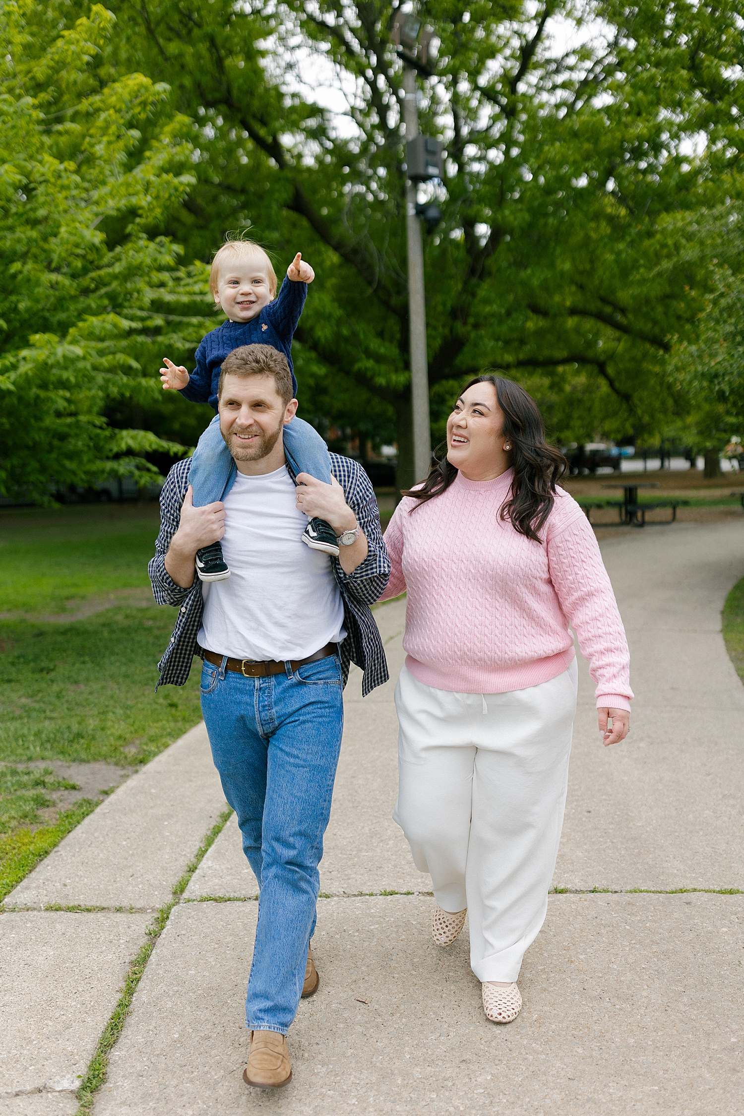 couple with their 1 year old walk on sidewalk by Rachel Andrade Photography
